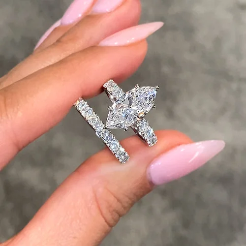 A marquise diamond ring held between fingers in daylight