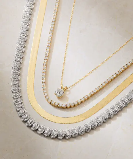 A diamond pendant layered with gold chains and diamond necklaces